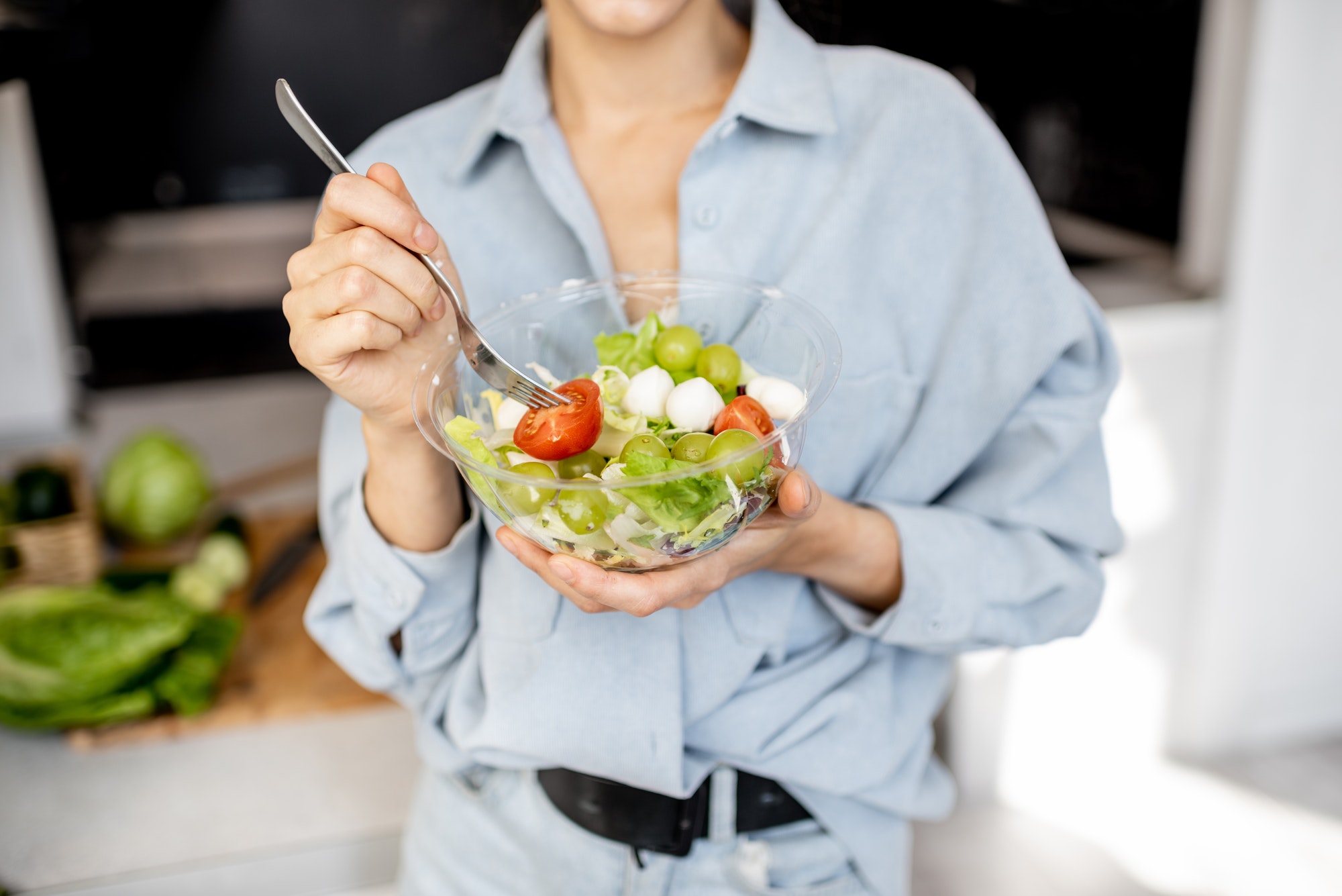 Woman eating healthy salad on the kitchen